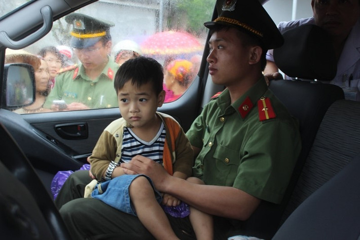 Bé trai được đưa ra khỏi xe gặp nạn vẫn còn hoảng sợ dù cảnh sát bế em lên xe.