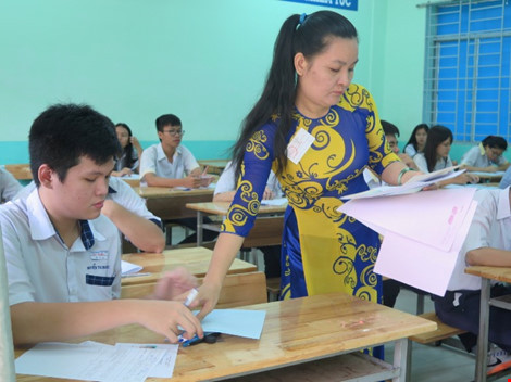 Giáo viên phát giấy nháp và giấy thi cho học sinh.