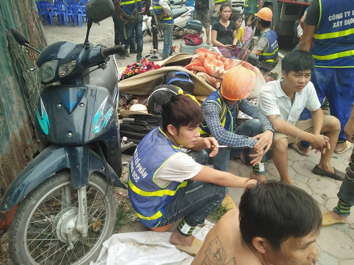 Nhiều công nhân ngồi tụ tập bên đường theo dõi việc chữa cháy.