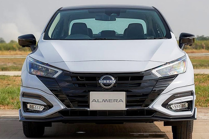 Quan sát Nissan Almera 2024 bản đang bán tại Thái Lan, sự thay đổi của phiên bản facelift được thể hiện khá rõ ở ngoại thất. Ở đầu xe, lưới tản nhiệt V-Motion đặc trưng của Nissan đã được chỉnh lại thành hình lục giác, chứa các nan ngang khổ lớn đặt trên nền màu bạc tươi sáng, tạo điểm nhấn nổi bật cho nền tổng thể màu đen.