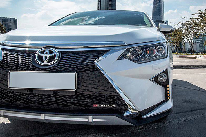 Nhờ cản trước và lưới tản nhiệt mới, nó không chỉ khiến cho xe sedan Toyota Camry trông sang trọng hơn, mà còn thể thao hơn bởi các hốc gió giả cỡ lớn. Những đường nét nổi đậm đầy góc cạnh của cản Lexus cũng “ton-sur-ton” với đèn pha hình tứ giác sắc sảo của Camry.
