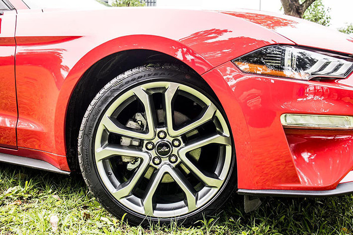 Ford Mustang kỷ niệm 55 năm ra đời là bản Premium nên xe sử dụng bộ mâm hợp kim màu titan với kích thước đến 20 inch 5 chấu kép hình chữ “V”. Gương chiếu hậu của xe không tích hợp đèn xi-nhan nhưng có tính năng cảnh báo điểm mù. Đuôi xe nổi bật nhờ cụm đèn hậu với thiết kế 3 dải LED ấn tượng, cặp ống xả đôi xuất hiện kèm đèn phản quang kết hợp với hệ thống cản sau góc cạnh.