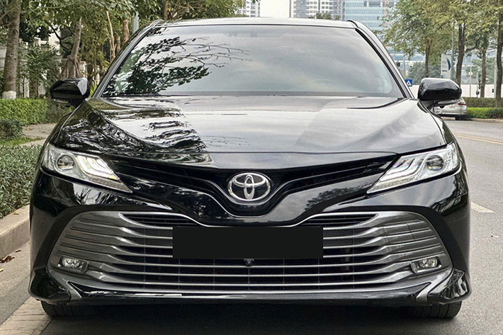 Về tổng thể, Toyota Camry 2019 đã qua sử dụng có kích thước dài x rộng x cao tương ứng là 4.885 x 1.840 x 1.445 (mm), chiều dài cơ sở đạt 2.825 mm và khoảng sáng gầm xe là 140 mm. Ở ngoại thất, đầu xe gây ấn tượng với cụm lưới tản nhiệt rộng kéo dài đến cản trước, đi kèm các thanh nhựa màu bạc nhũ xếp lớp.