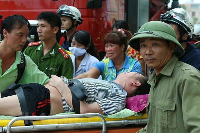 Lực lượng chức năng phải sử dụng rìu, búa phá cửa một số phòng để giải cứu những người bị mắc kẹt không thể di chuyển ra ngoài lan can do khói xộc vào quá nhiều. Ảnh: Vietnamplus.