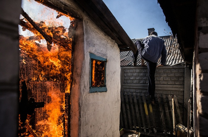 Một ngôi nhà bốc cháy sau khi trúng đạn cối ở Donetsk.