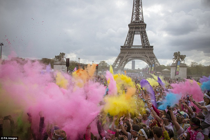 Mọi người tung bột màu vào nhau khi về đích dưới chân tháp Eiffel. (Nguồn: Daily Mail)