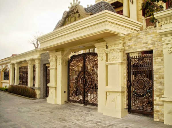 Cổng hợp kim được trang trí màu nâu đồng giả cổ, kết hợp với màu sơn vàng nhạt tạo nên sự hoàn hảo cho ngôi biệt thự phong cách châu Âu cổ. Ảnh: Hangraodep.