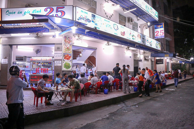Cách đó không xa, một quán nhậu bày bàn ghế chiếm vỉa hè dài gần 50m cho khách ngồi ăn uống.