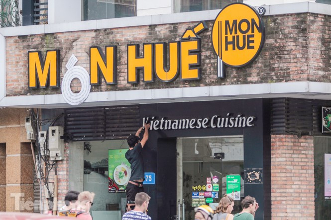Công nhân đang tháo dỡ biển của cửa hàng Món Huế trên phố Tràng Thi.