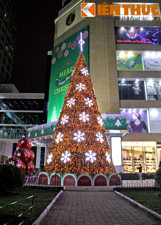Bên cạnh cây thông Noel khổng lồ là những quả cầu màu đỏ gắn bông tuyết trắng.