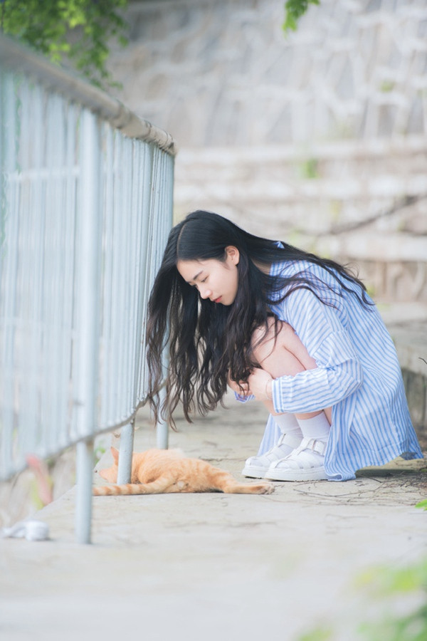 Hu Anru chơi đùa với một chú mèo ở góc sân trường.