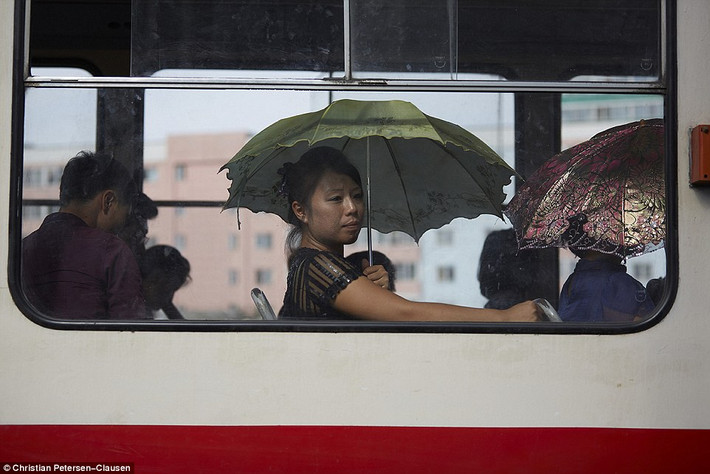 Các hành khách nữ vẫn phải dùng ô để che nắng khi ngôi trên xe bus.