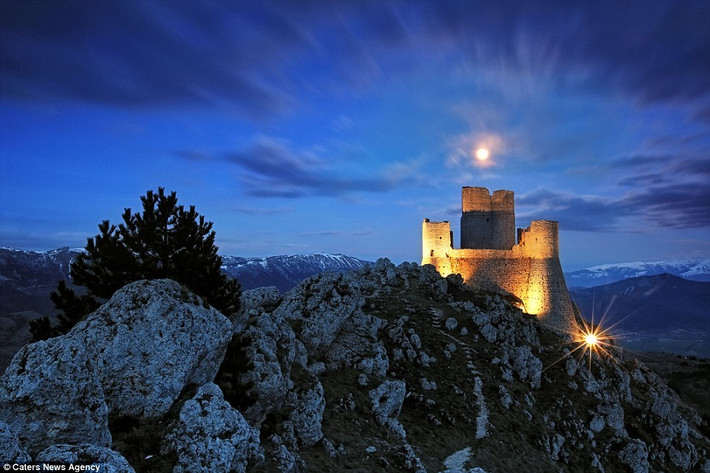 Lâu đài cổ được chiếu sáng rực rỡ trên đỉnh núi ở Rocca Calascio, Italy.