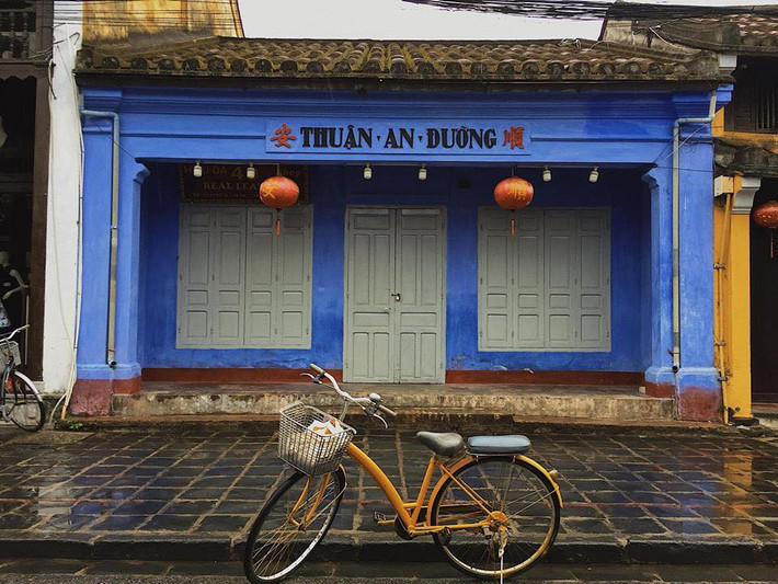 Chiếc xe màu vàng, nổi bật trên nền xanh da trời của một cửa tiệm tại phố cổ Hội An.