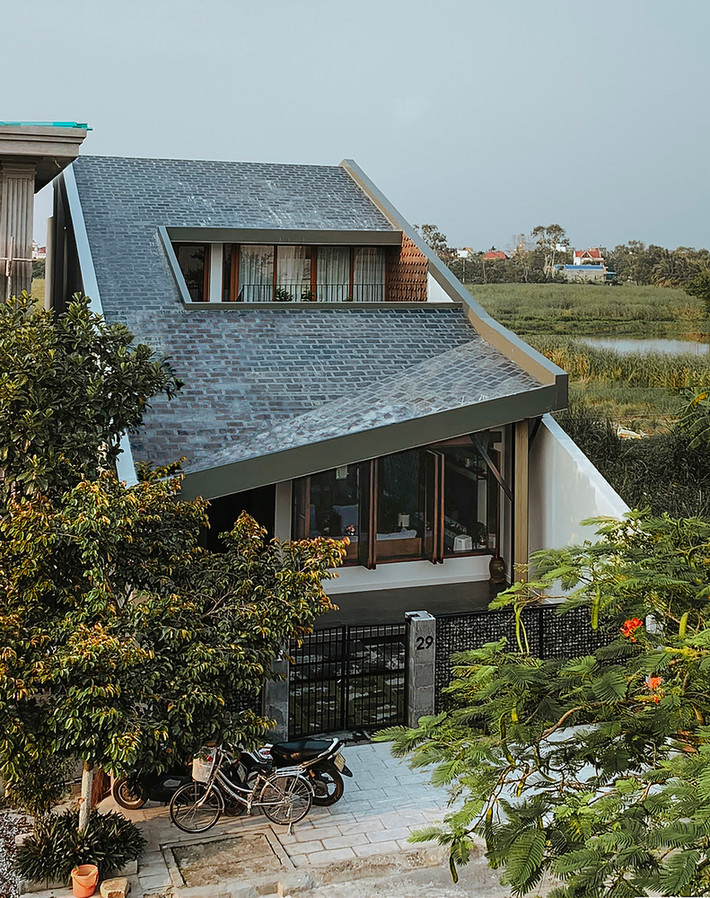 Nhà thiết kế 1,5 tầng, có điểm nhấn là mái nhà dốc xoè rộng, mái được đổ bê tông, chống nóng cẩn thận và lát đá.