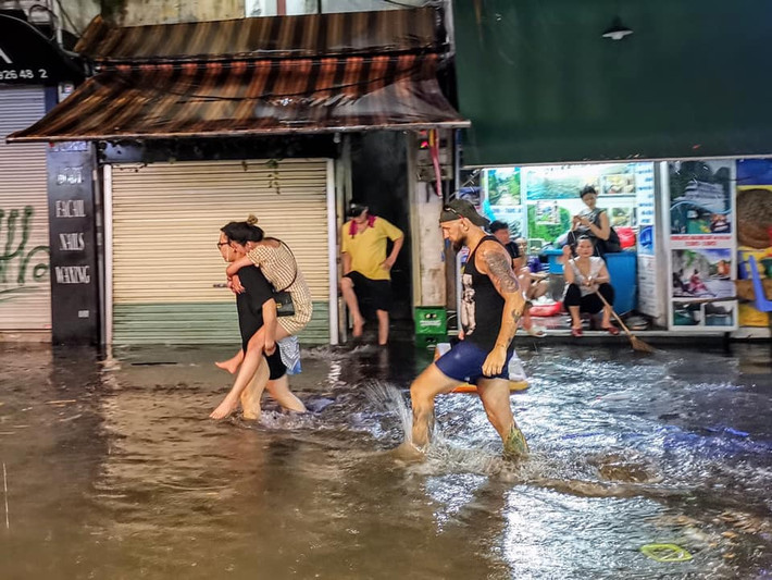 Nhiều du khách nước ngoài phải đội nilon chùm mưa và cõng nhau để tới điểm ăn uống.