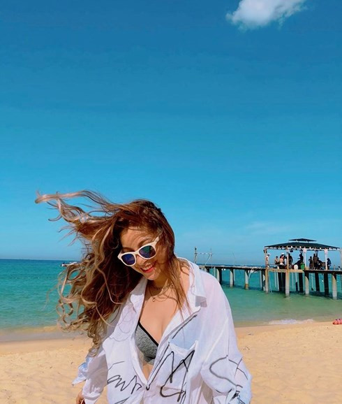 Cụ thể trong loạt ảnh mới của mình, Nhật Lê diện bikini một mảnh màu đen và khoác áo sơ mi trắng trong suốt bên ngoài.