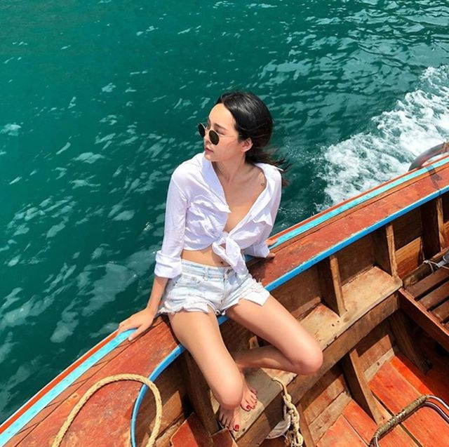 Cô nàng này chọn mặc kiểu áo crop top thắt nơ biến tấu từ sơ mi trắng với quần short jeans, tạo nên bộ đôi đi biển không thể sexy hơn.