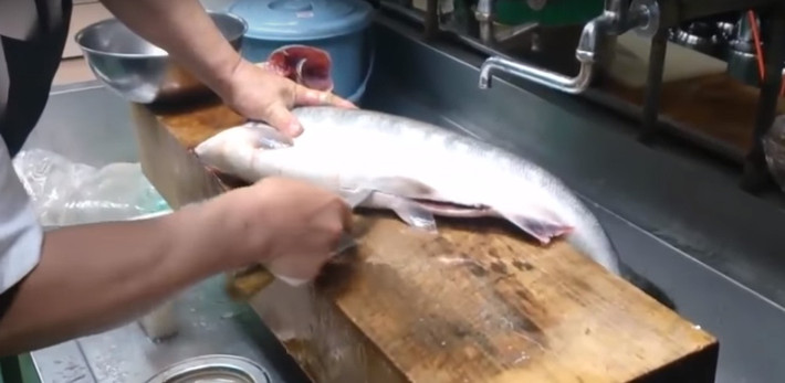 Sau đó dùng mũi dao sắc, nhọn rạch bụng cá hồi từ dưới lên.