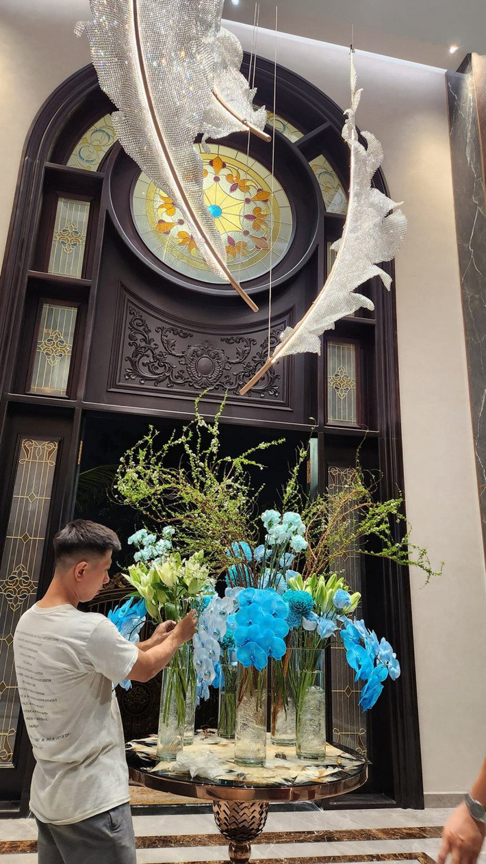 Bình hoa trong suốt được trang trí bằng bông hoa màu xanh dương nổi bật kết hợp loại cây cành dài đầy nghệ thuật.