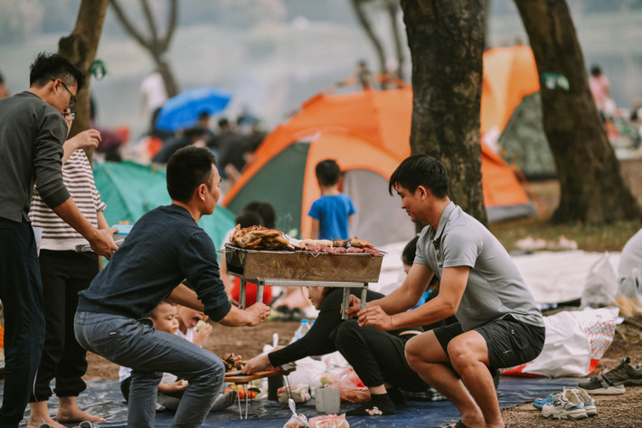 Các gia đình mang theo lều cắm trại, tự do thư giãn, tận hưởng bầu không khí thoáng đãng dưới rừng cây.