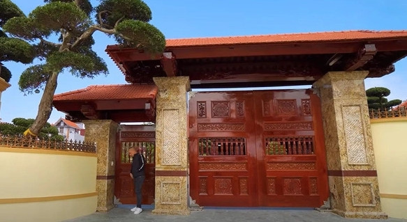 Cổng vào bằng gỗ bề thế, trụ cổng ốp đá sang trọng.