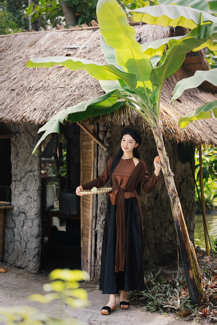 Lọ Lem chọn áo tứ thân màu nâu trầm kết hợp yếm đào, tóc buông xõa tự nhiên, trang điểm nhẹ nhàng phù hợp với không gian làng quê yên bình.