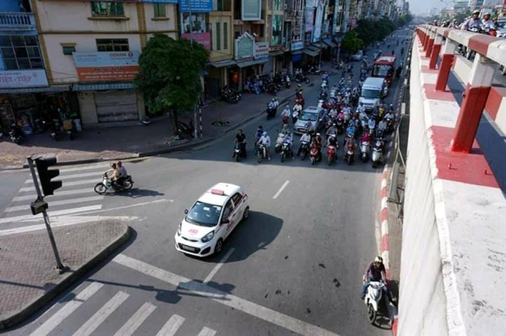 Nhiều phương tiện xe máy khi dừng đèn đỏ đã chọn giải pháp đứng dưới bóng cây, cách vạch kẻ quy định chờ đèn đỏ cả chục mét.