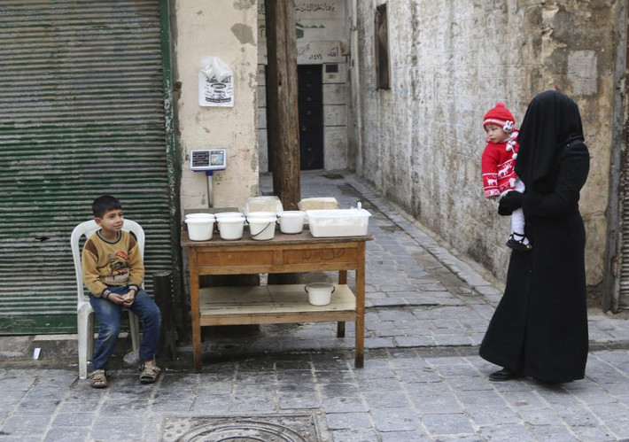 Cậu bé ngồi bán sữa chua trên đường phố ở Aleppo.