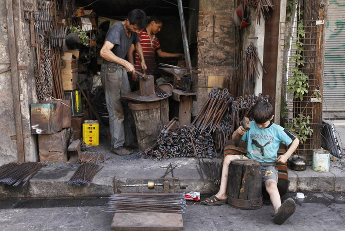 Cậu bé phụ việc cho bố tại xưởng rèn ở thành phố Aleppo.