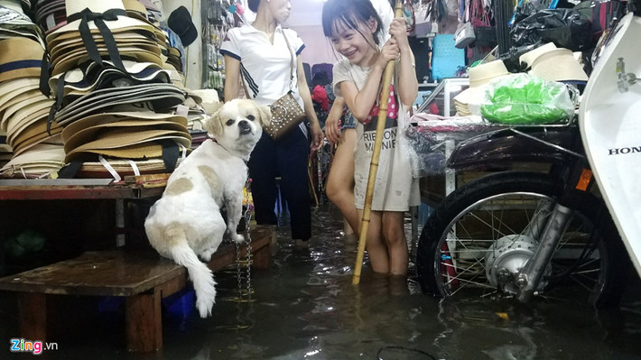Tuy nhiên, nhiều căn nhà mặt phố gần đó không tránh khỏi việc bị nước "tấn công". Một cửa hàng kinh doanh thời trang nhanh chóng kê đồ lên cao.