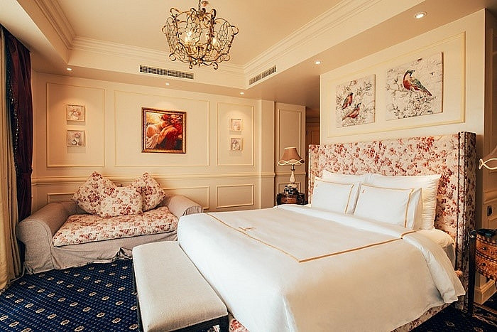 Phòng ngủ trang trí nhiều tranh ảnh có sofa phụ và đèn chùm.