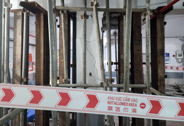 Hai cột dưới tầng để xe của tòa nhà bị nứt toác, vết nứt chạy ngang dọc từ chân cột lên đến trần nhà. Lực lượng chức năng cho gia cố thêm hệ thống giàn giáo bằng sắt chống đỡ xung quanh chân các cột nhà bị xuống cấp.
