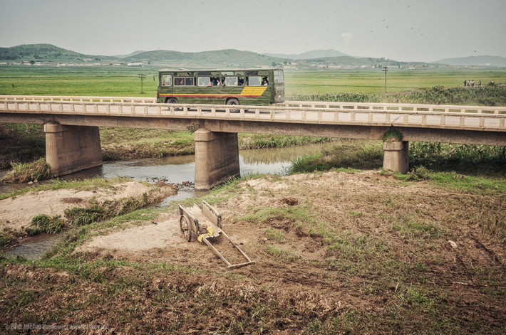 Chiếc xe bus cũ kỹ chạy qua cầu dọc đường ray tàu hỏa.