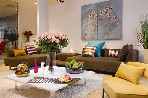Màu nâu trầm của sofa kết hợp màu vàng của ghế, màu trắng của bàn trà..tạo nên không gian phòng khách tươi vui, rực rỡ. Ảnh: Bindo.