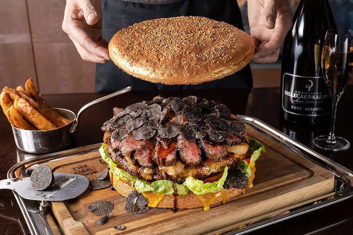 Bánh burger được tạo thành từ một miếng thịt bò wagyu nặng 1 kg, gan ngỗng, rau diếp, phô mai cheddar, nấm cục đen truffle, cà chua và hành tây.