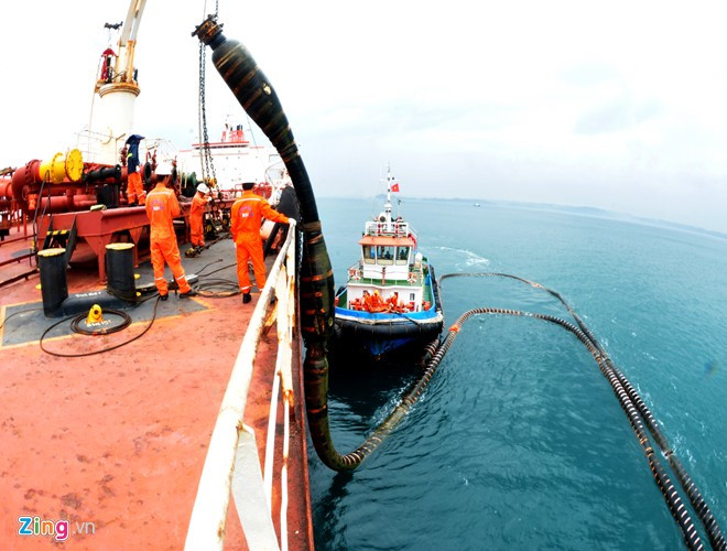 Các kỹ sư, công nhân vận hành hệ thống cẩu trục nâng ống dẫn mềm từ từ kéo lên boong tàu chở dầu thô.