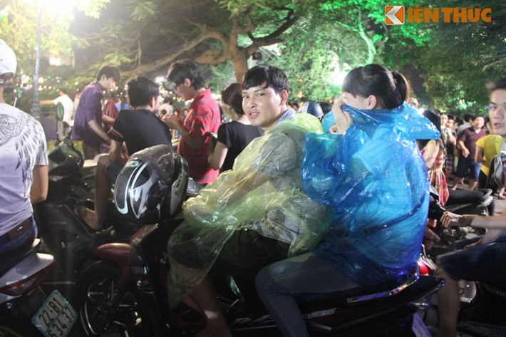 Tại Hồ Hoàn Kiếm, dòng người nối nhau mặc áo mưa chờ xem bắn pháo hoa.