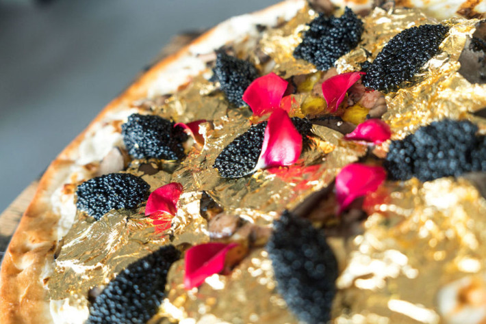Chiếc pizza có giá 2.000 USD của nhà hàng Industry Kitchen trên phố South Street Seaport ở Manhattan (New York, Mỹ) được giới thiệu vào cuối năm 2016. Bánh được làm từ những nguyên liệu cao cấp như phô mai Stilton trắng, gan ngỗng, nấm truffle của Pháp, trứng cá muối Osetra và được trang trí bằng những miếng vàng lá. Ước tính giá cho mỗi một lần cắn là 50 USD và thực khách phải đặt trước ít nhất hai ngày nếu muốn được thưởng thức chiếc bánh này. Ảnh: Industry Kitchen.