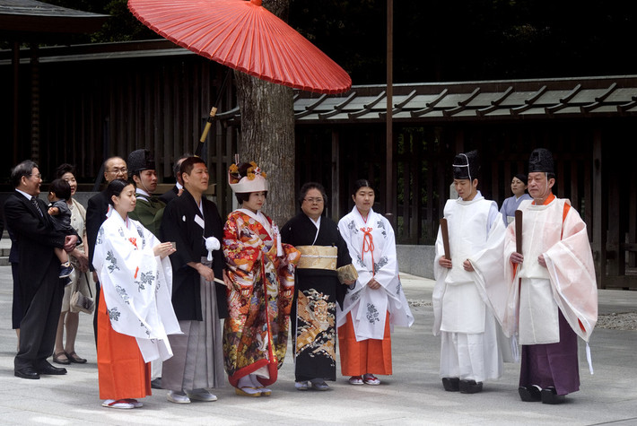 Trong bước thứ nhất của buổi lễ - “Sanshin”, cặp đôi sẽ đi qua sân đền vào phòng chờ. Cả hai phải có mặt trước thần linh. Đôi khi họ đi phía sau thần chủ và các vu nữ dưới một chiếc ô màu đỏ. Bước thứ hai là “Haiden chakuza”, khi mọi người ngồi xuống. Cô dâu và chú rể ngồi gần thần linh nhất. Cô dâu ngồi bên trái và chú rể bên phải.