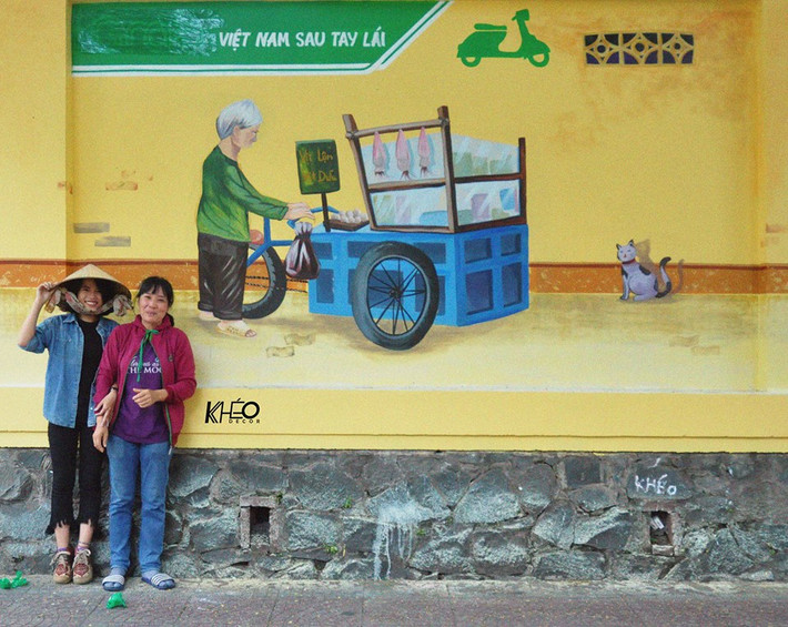 Sự phấn khích của một cô bán hàng rong nơi bức tường được các bạn trẻ nhóm "Việt Nam sau tay lái" thực hiện sơn sửa. Ảnh trong bài: KIds Dương.