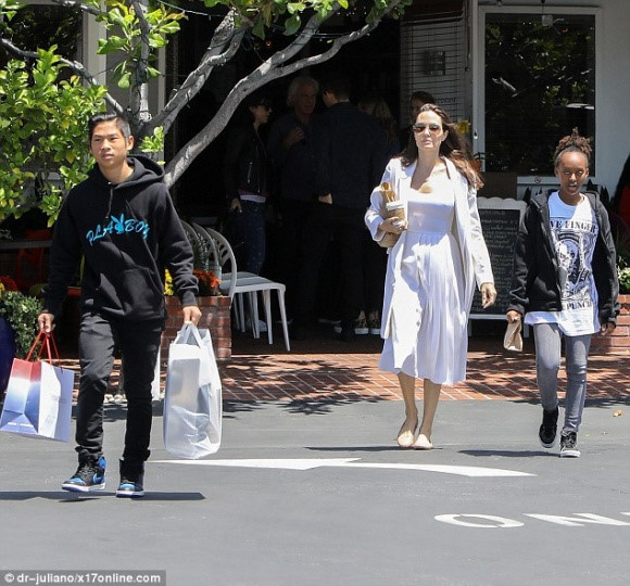 Diễn viên Angelina Jolie cũng bị bắt gặp ra ngoài mua sắm một số đồ cần thiết cùng với hai con là Pax Thiên và Zahara. Anh trai Pax Thiên ra dáng một cậu thanh niên chững chạc khi giúp mẹ và em gái xách đồ.