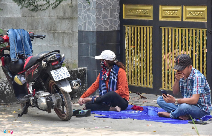 Hàng trăm người đội nắng đứng theo dõi từ xa, quay điện thoại. Có nhóm còn dùng cả nylon trải chỗ mát gần khu vực vây bắt nằm nghỉ.