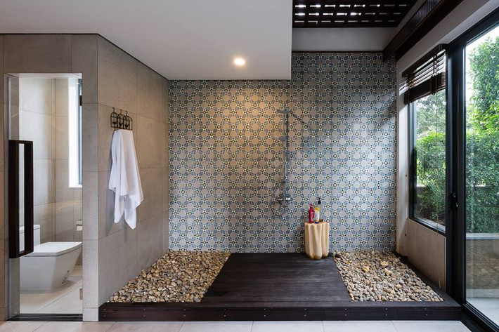 Phòng tắm thiết kế mở, sử dụng gạch bông ốp tường, trải sỏi dưới sàn.