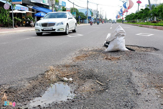 Người dân phường Trần Quang Diệu (TP Quy Nhơn) mang bao cát, lốp xe đặt ngay những vị trí ổ gà trên đường Tây Sơn cảnh báo nguy hiểm.