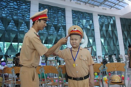 Bé Đỗ Tuấn Dũng được các chiến sỹ hướng dẫn tận tình các hoạt động của CSGT. Nguồn ảnh: Lao động.