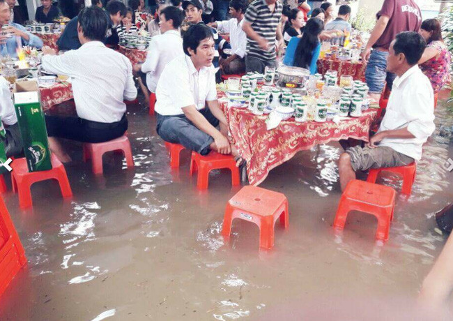 Đám cưới mùa lũ có những khó khăn, vất vả song hơn hết, cô dâu chú rể và họ hàng, người thân vẫn rất vui vẻ trong ngày đại hỉ. Mới đây, hình ảnh một đám cưới đã diễn ra trong thời tiết mưa lũ ở Khánh Hòa khiến nhiều người quan tâm. Khách đến tiệc cưới xắn quần ngồi ghế nhựa ăn tiệc.