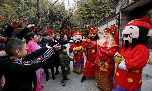 Ngày Thần Tài ở Trung Quốc, nhiều cửa hàng mở cửa, phát phiếu lì xì cho khách. Ảnh: News.