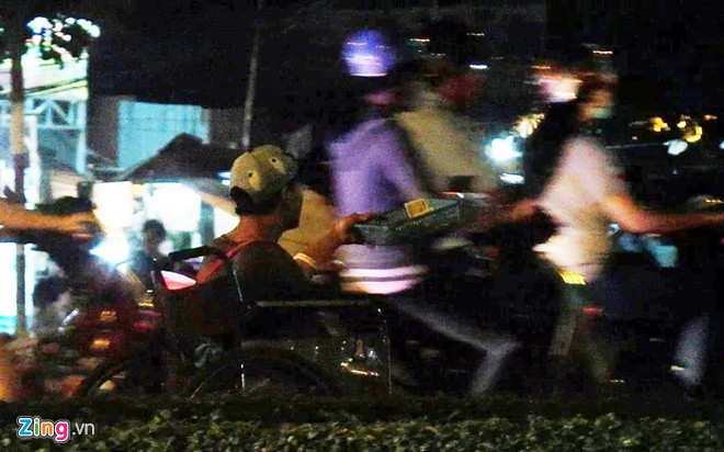 Một thanh niên tàn tật khoảng 25 tuổi ăn xin tại giao lộ Nguyễn Văn Linh - đường dẫn cầu Tân Thuận. Anh cho xe chạy tới chạy lui, len lỏi vào cả dòng xe cộ lưu thông để xin tiền. Xin được nhiều, anh sẽ gom lại đưa cho người đàn ông ngồi gần đó, chỉ để lại vài ngàn đồng tiền lẻ. Hai người hoạt động tại khu vực này từ chiều tối đến khuya, kiếm khá.