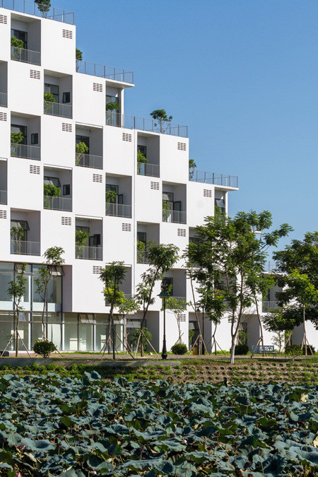 Tòa nhà có tổng diện tích sử dụng là 11.065 m2. Mặt tiền của tòa nhà được thiết kế ô vuông đặc rỗng so le nhau tạo nhịp điệu đơn giản nhưng ấn tượng. Giữa các ô được trồng cây xanh bảo vệ tòa nhà không bị mặt trời chiếu trực tiếp nhưng vẫn đảm bảo đủ ánh sáng tự nhiên, không cần dùng đèn điện vào ban ngày. Ảnh: Website ĐH FPT.